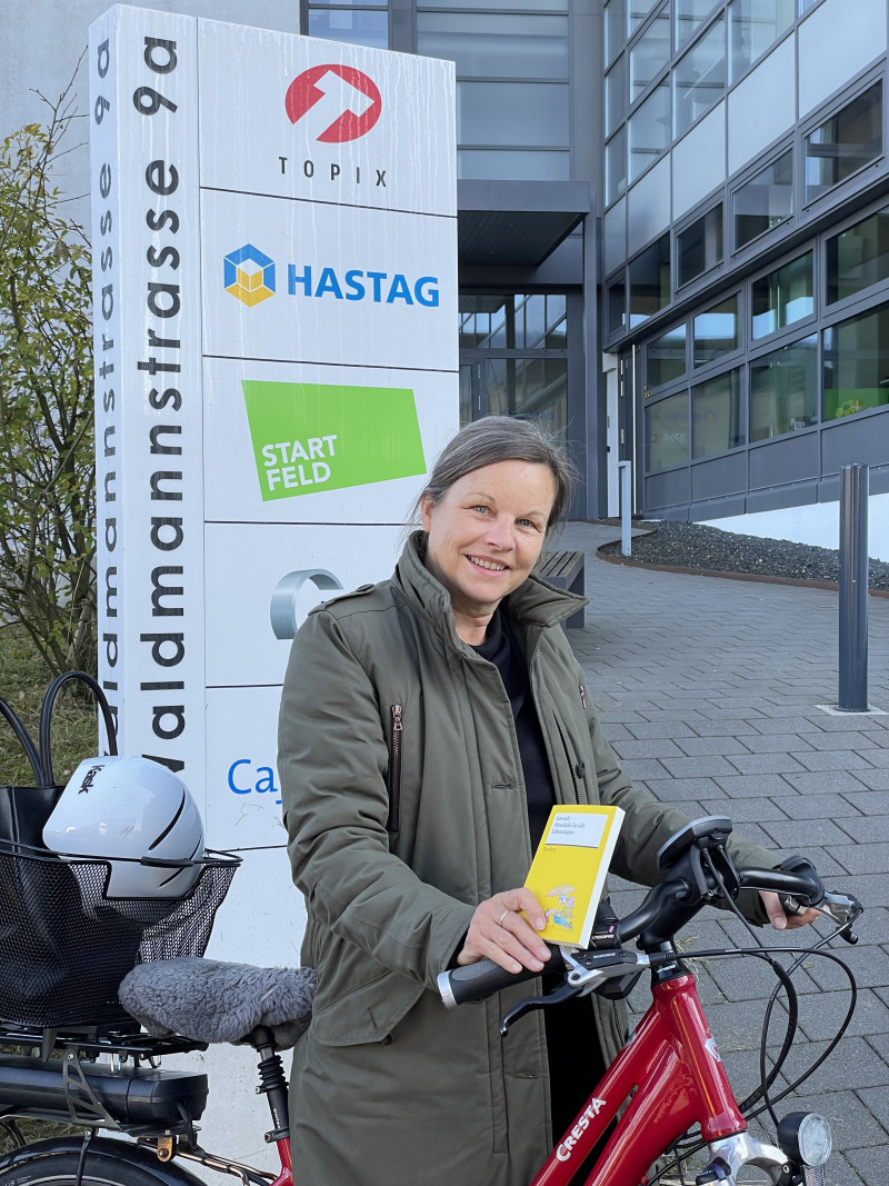 Frau auf Velo mit Buch